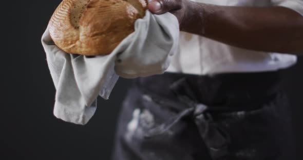 Video of cook holding loaf of bread on black background