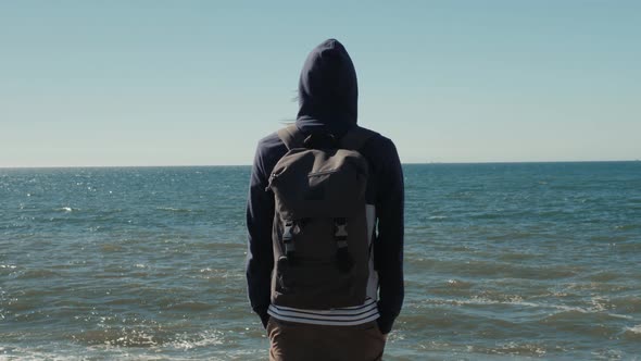 Man Traveler with Backpack Relaxing Outdoor Sea and Rocks Coastal on Background Freedom Lifestyle