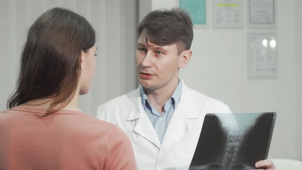 Mature Doctor Examining Spinal Xray of a Female Patient