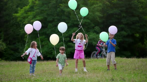 Group of Happy Children Playfully Running with Multicolored Balloons