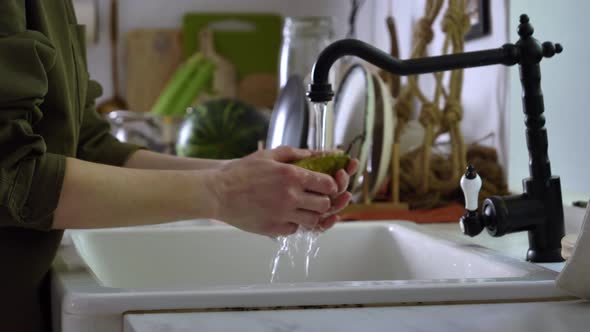 Woman washing pear under water at kitchen