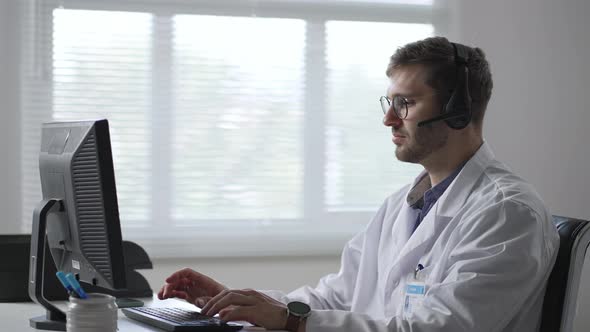 Male Doctor or Nurse with Headset and Computer Working at Hospital
