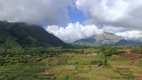 Aerial view of Mount Pergasingan Hill with hiding clouds during sunny day on Lombok.