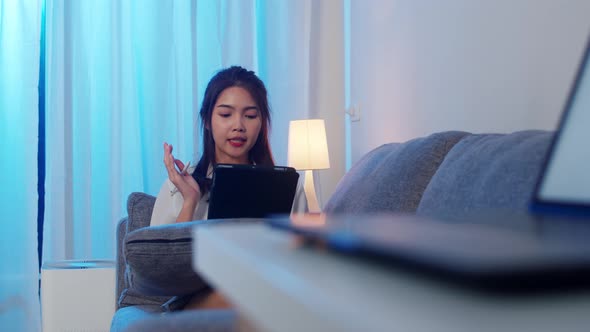 Asian businesswoman using tablet talk to colleagues about plan in video call while working from home