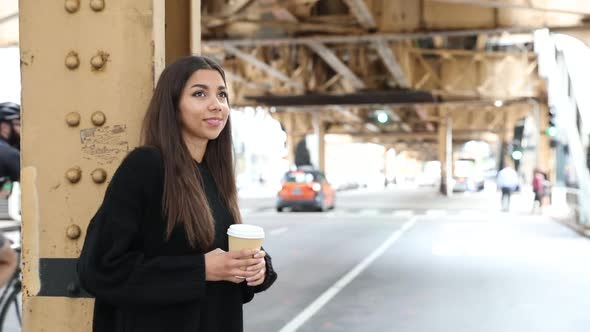 Girl by a city street with a cup of coffee