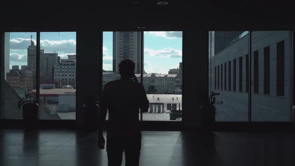 A Man in a Dark Corridor Speaks on the Phone, Looking at the Box Office