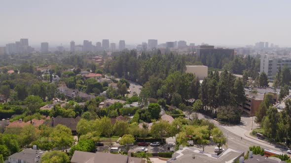 Aerial of houses and vehicles riding on road in city on a sunny day