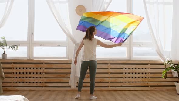 Female Holding LGBT Gay Flag in Hands and Waving on Sunset in Sunny Rays