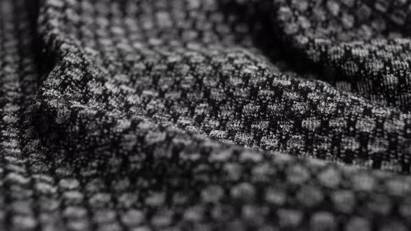 Black fabric texture with a dotted pattern. Crumpled synthetic spotted surface. Macro