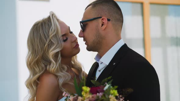 Languid Bride with Bouquet Looks at Fiance on City Street