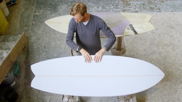 Man examining a surfboard 4k