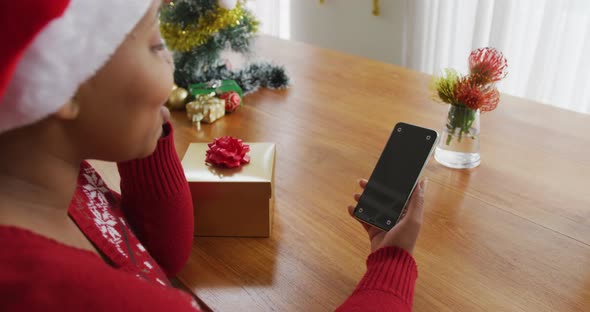 Happy african american plus size woman in santa hat, making video call using smartphone at christmas