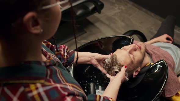 Barbershop: female barber washes the head of male client