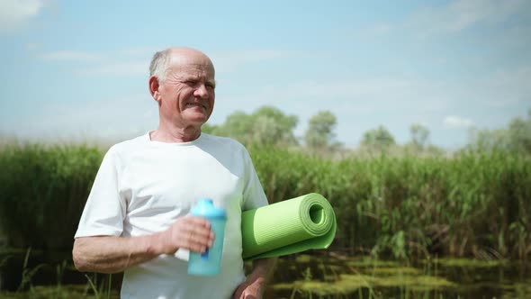 Portrait of Old Man with Rug for Yoga or Meditation in Hands To Take Care of Health and Drink Clean