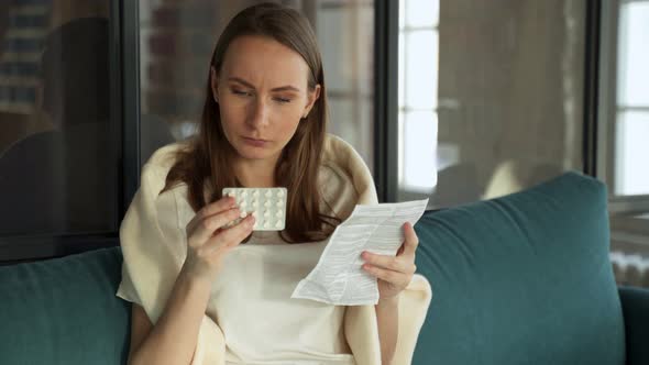 Young Woman with Pills and Instructions Sitting on the Couch