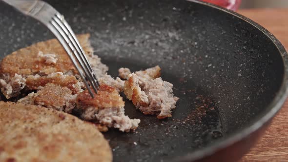 Fish cutlets in a frying pan with oil. Male hand with a fork.