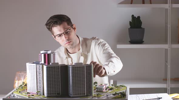 Young Business Man Measuring a Model of High Building.