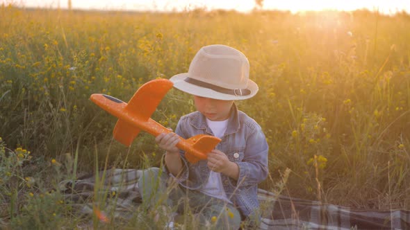 Happy Little Boy Playing with a Toy Airplane in Nature During Sunset. Dreams of Traveling Concept.