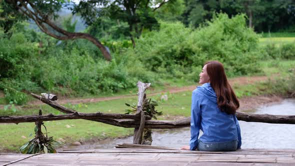 A young woman sitting by the river in rural village