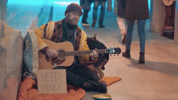 A Tramp is Playing the Guitar for Money