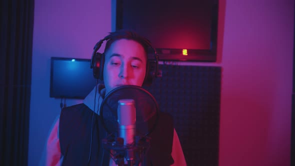 A Man in Hoodie Rapping Through the Pop-filter in the Microphone - Recording His Track