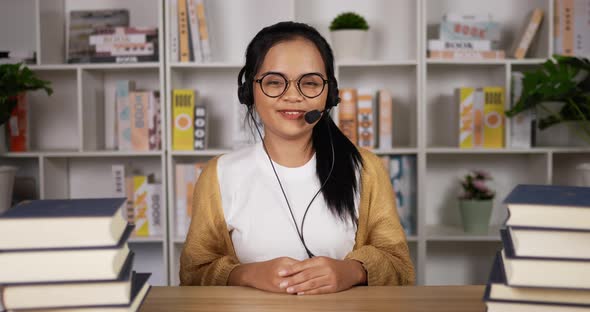 Happy female student in headphones and glasses talking at camera