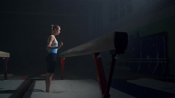 Sporty Teenager Girl is Training with Balance Beam in Dark Gymnastic Hall Discipline of Artistic