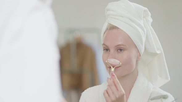 Pretty Female Doing Facial Massage in Bright Bathroom