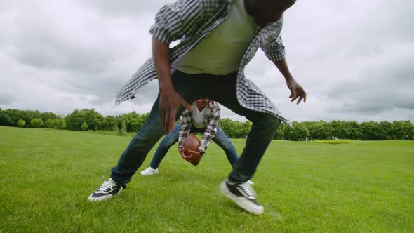 Joyful Black Family Practicing American Football Outdoors