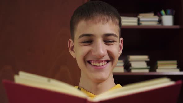 young student is reading a book and laughing 