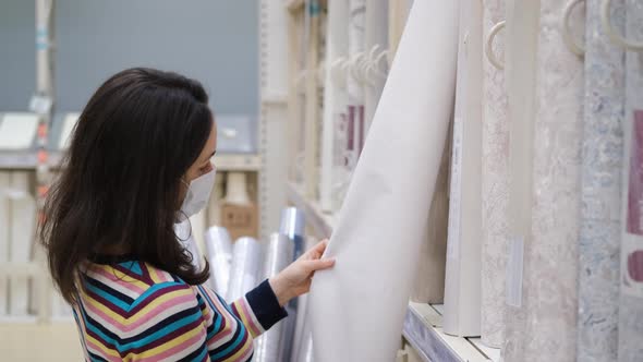 Young Woman Choosing Wallpapers in Hardware Store