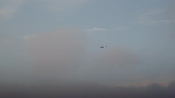 Helicopter flying in blue cloudy sky