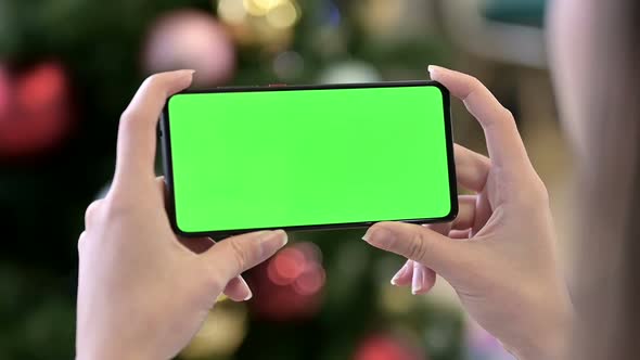 Holding Horizontal Chroma Key Screen Smartphone Near Christmas Decoration