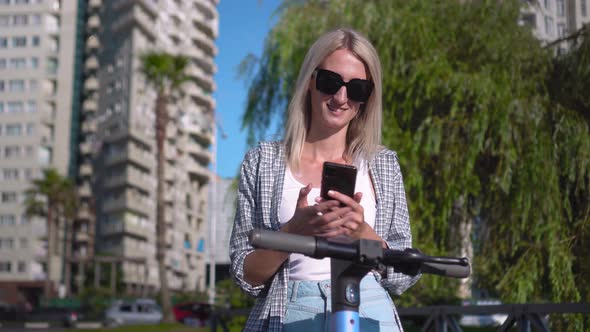 a woman uses app in her smartphone to rent electric scooter.