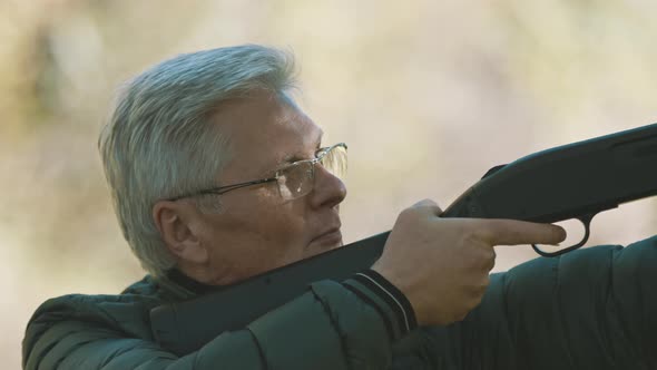 Elderly Gray Haired Man Holding a Gun in His Hands. Hunting Season