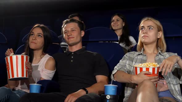 Handsome Young Macho Man Hugging Two Girls at the Cinema