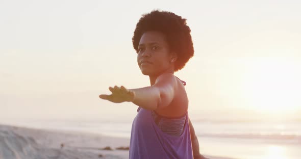 Happy african american woman practicing yoga on sunny beach