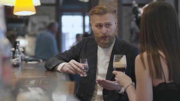 Brunette Woman and Confident Blond Bearded Man Sitting at the Bar