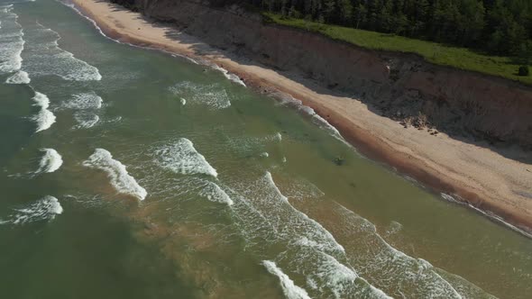 Scenic Slow Motion Drone Fligh Down Above Turquoise Baltic Sea with Waves and Sand Cliff