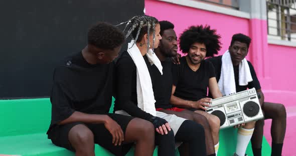 Group of young african people listening music from vintage boombox stereo outdoor after basketball m