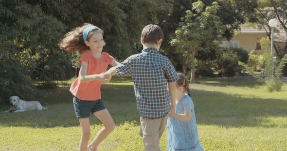 Three kids playing together outdoors on the grass, running around