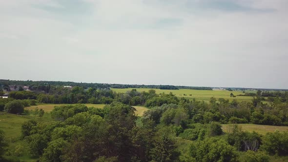 Beautiful daytime aerial drone shot slowly panning across fields towards a small rural farm town