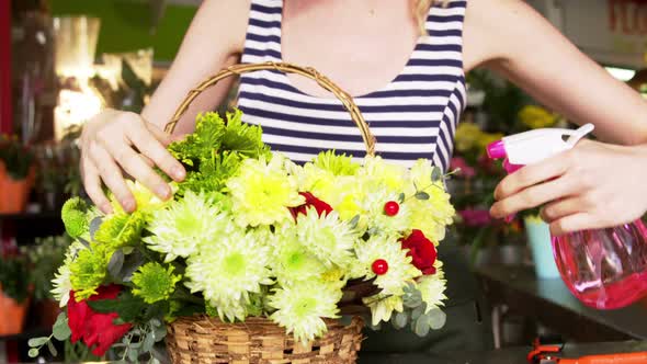 Female florist spraying water on flowers in flower shop