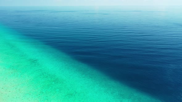 Wide aerial travel shot of a white paradise beach and blue water background in 4K