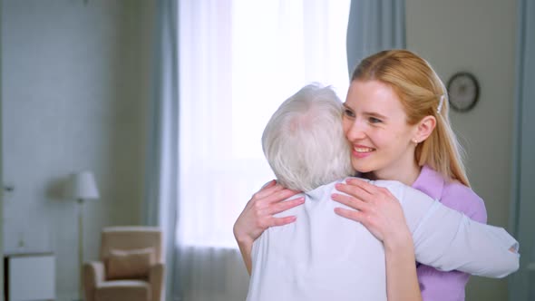 Elderly mother and young daughter hugging at home