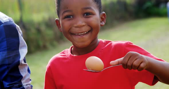 Happy boy holding egg and spoon in backyard 4k