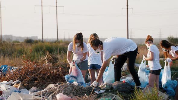 Group of Eco Volunteers Cleaning Up Area of Dump Near the Field During Sunset