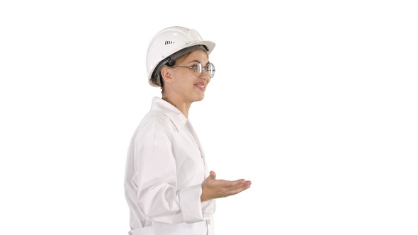 Young scientist in lab coat and hardhat walking and saying