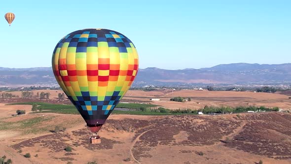 Aerial orbit of a hot air balloon floating over the Southern California wine country landscape