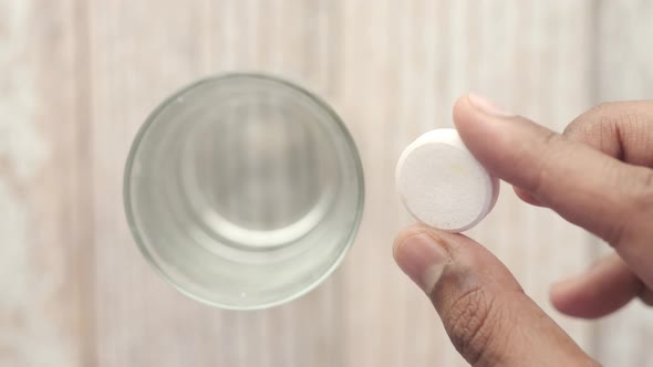 Effervescent Soluble Tablet Pills and Glass of Water on Purple Background